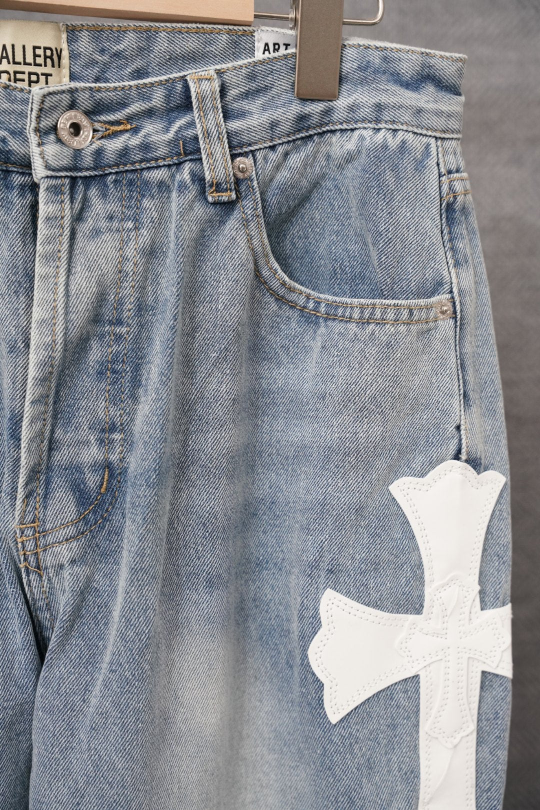 Light blue denim pants with front pockets and white cross applique