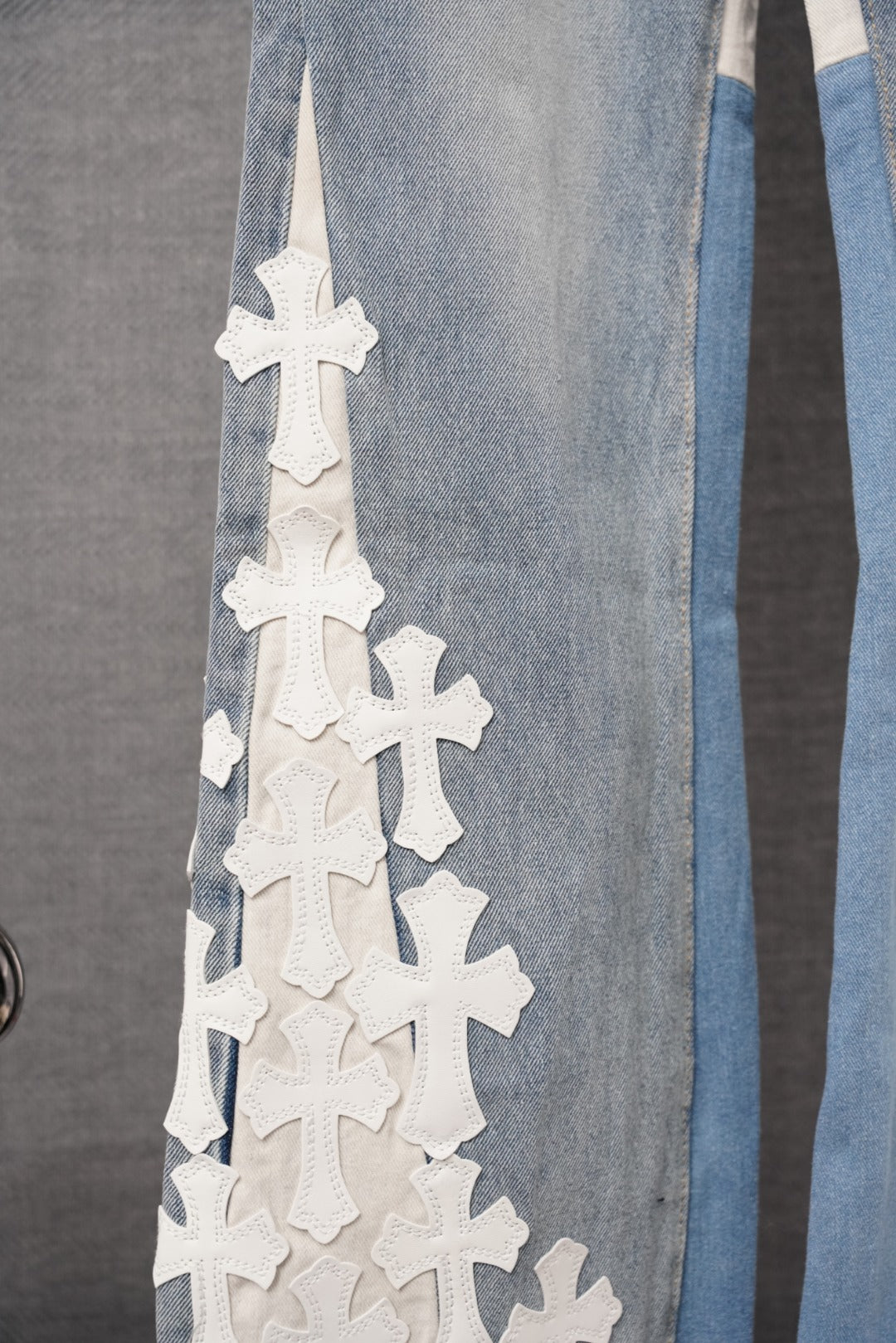 Light-wash denim pants with stacked white cross appliques on the side