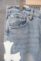 Light blue denim pants with back pocket and white cross patch