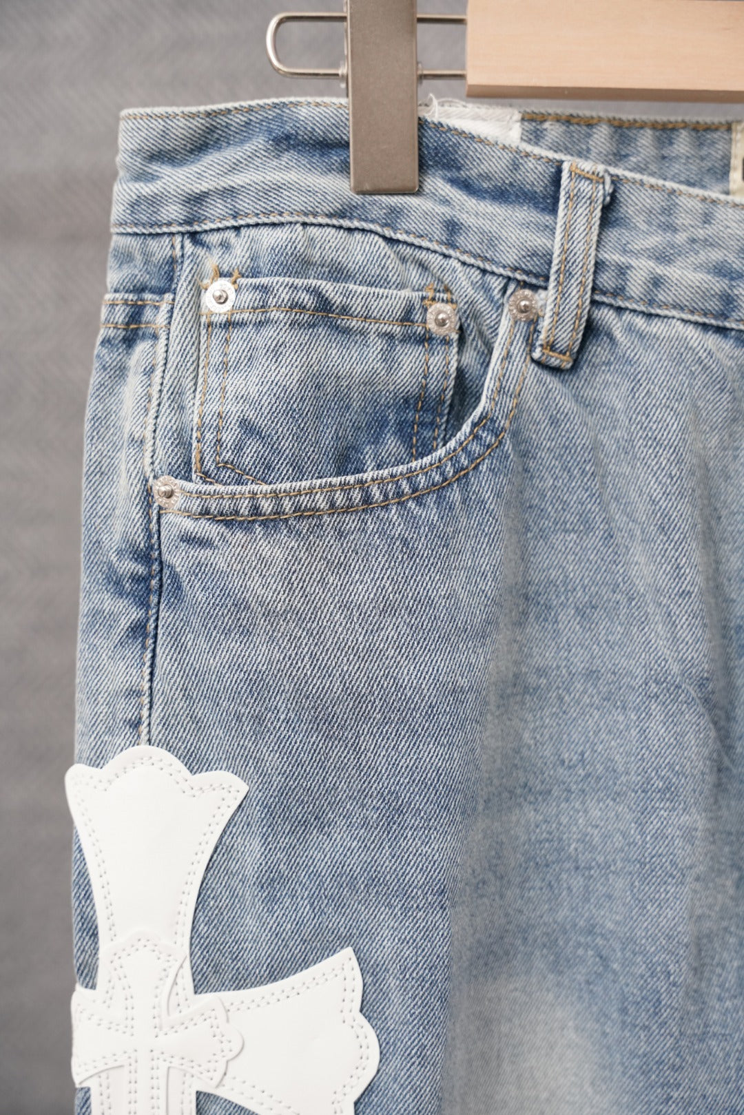 Light blue denim pants with back pocket and white cross patch