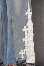 Light blue denim pant leg with tall vertical row of white cross appliques