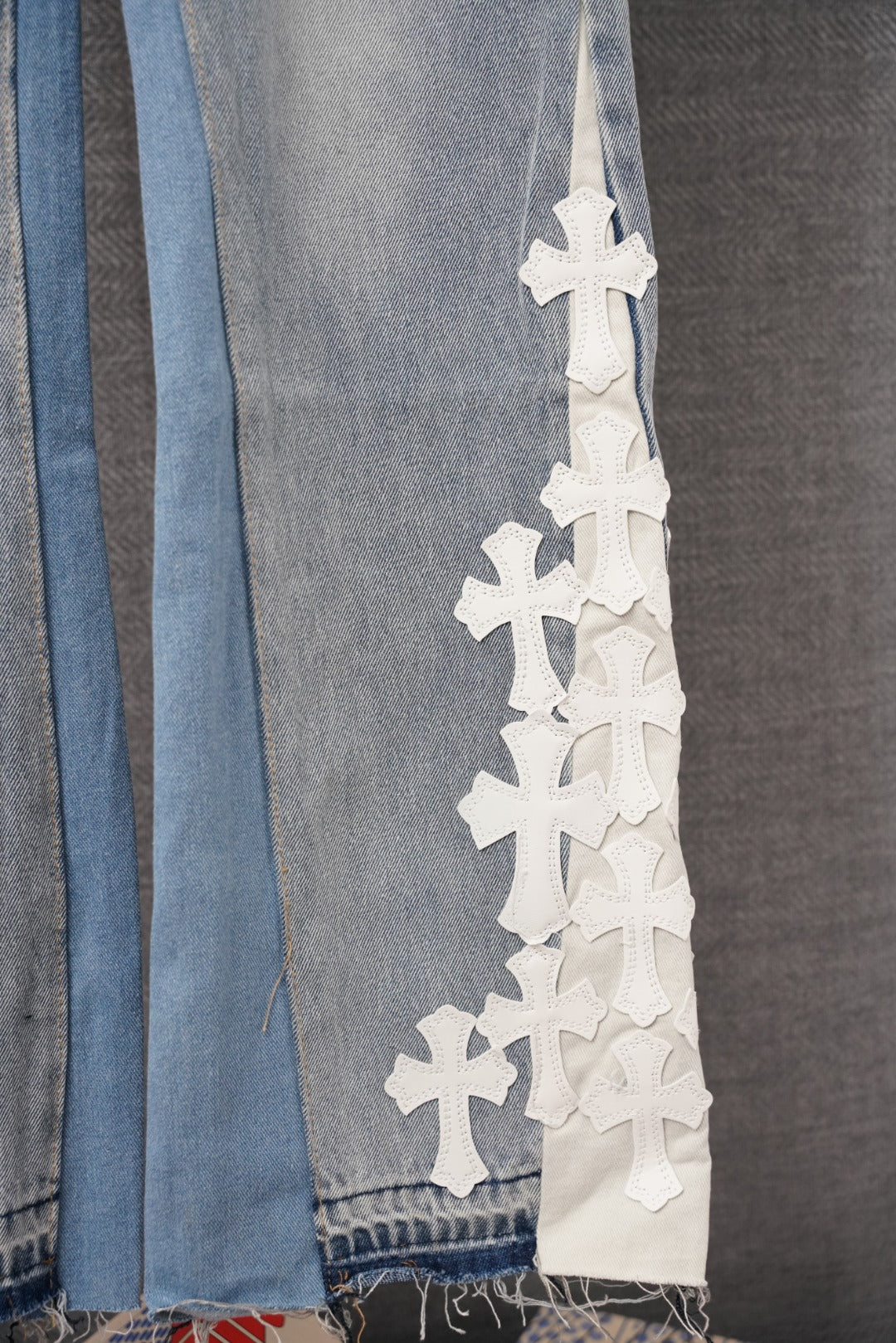 Light blue denim pant leg with tall vertical row of white cross appliques