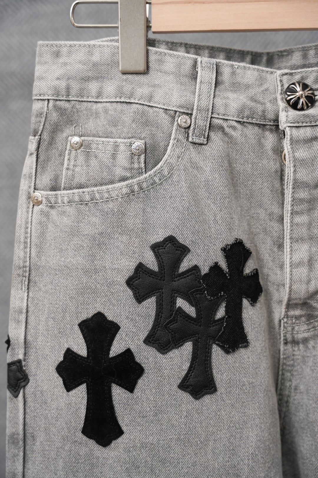 Light-wash denim pants front pocket with black cross applique detail