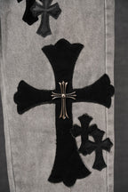 Light-wash denim pants with large black cross applique on the front