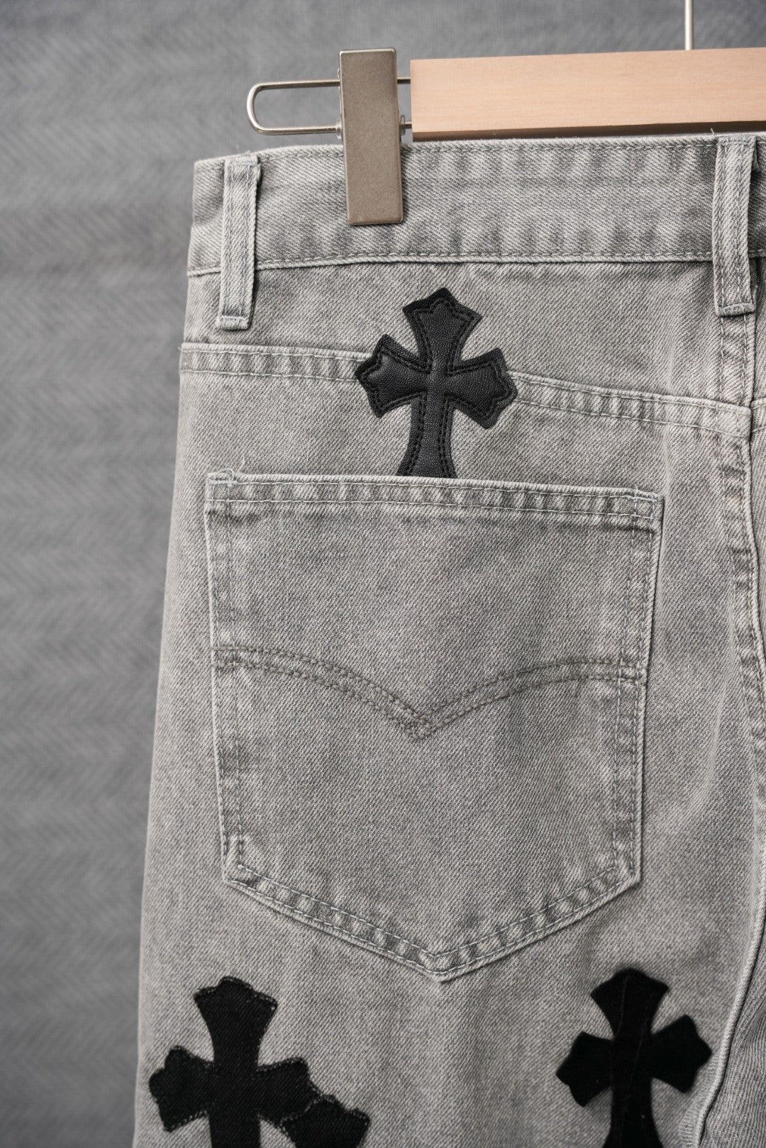 Light-wash denim pants close-up of back yoke and black cross appliques