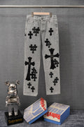 Light gray denim pants with bold black cross patches, front view.