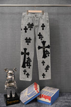 Light gray denim pants with bold black cross patches, front view.