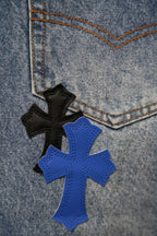 Close-up of denim with black and blue cross patches