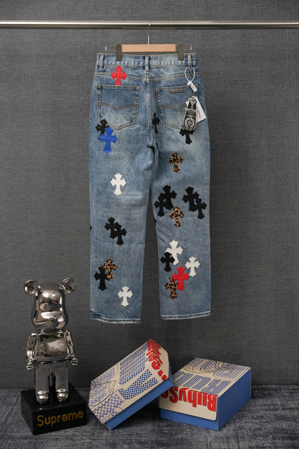 Light blue denim pants with embroidered cross patches across the legs and back