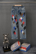 Light blue denim pants with multicolor embroidered cross patches on the front