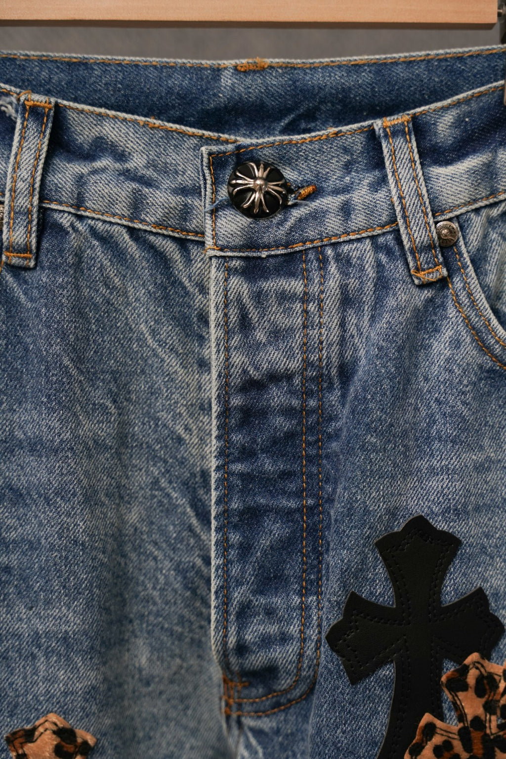 Denim waistband and fly with button; cross patch near the hem