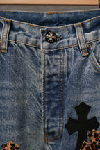 Denim pants waistband with metal button and embroidered cross patches near hem
