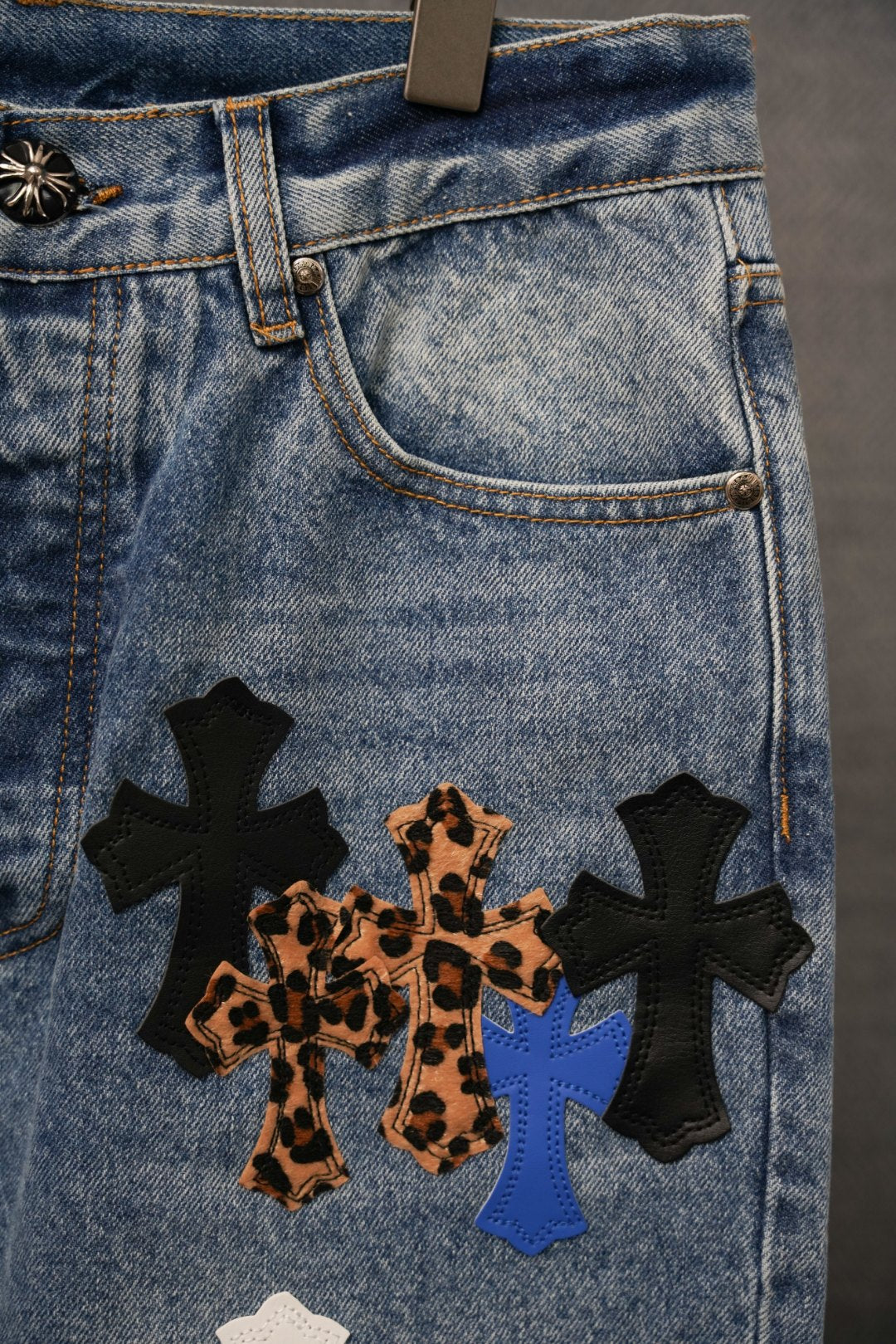 Back pocket area of light blue denim pants with cross appliques