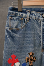 Front upper leg of light blue denim pants with cross patches near pockets
