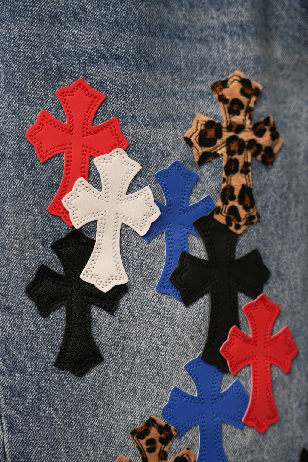 Close-up of embroidered cross patches in red, white, blue, and black on denim