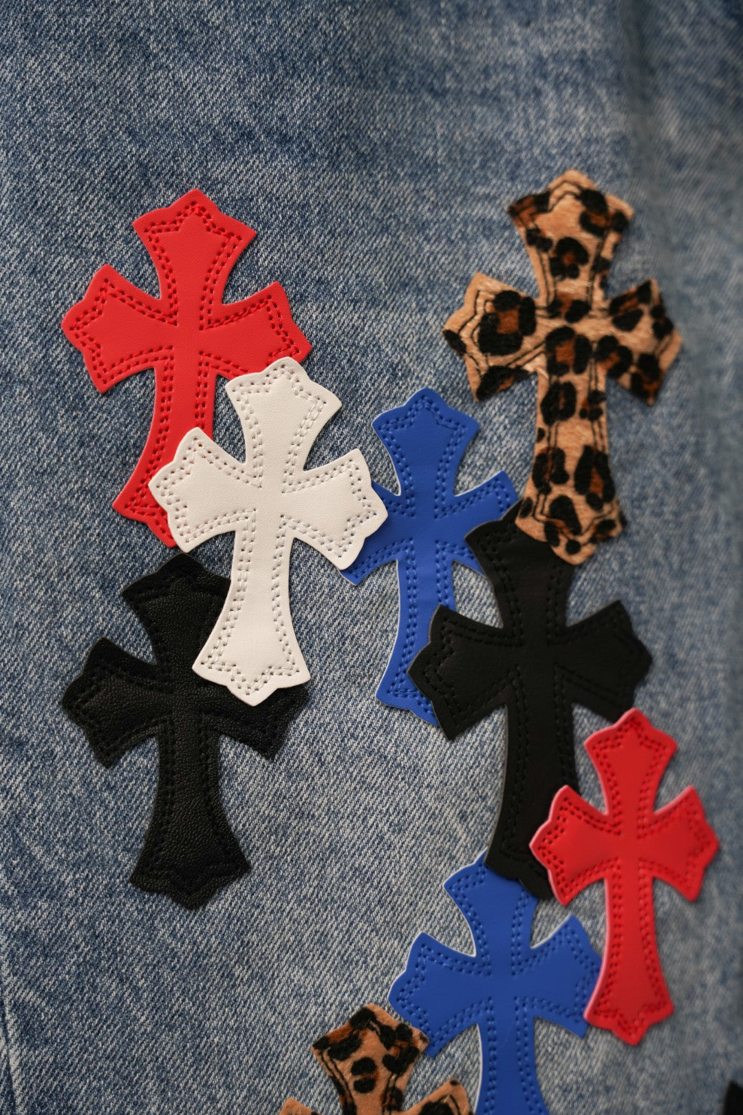 Close-up of embroidered cross patches in red, white, blue, and black on denim
