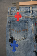 Blue denim pants with cross patches on back pocket in red, blue, black, and white