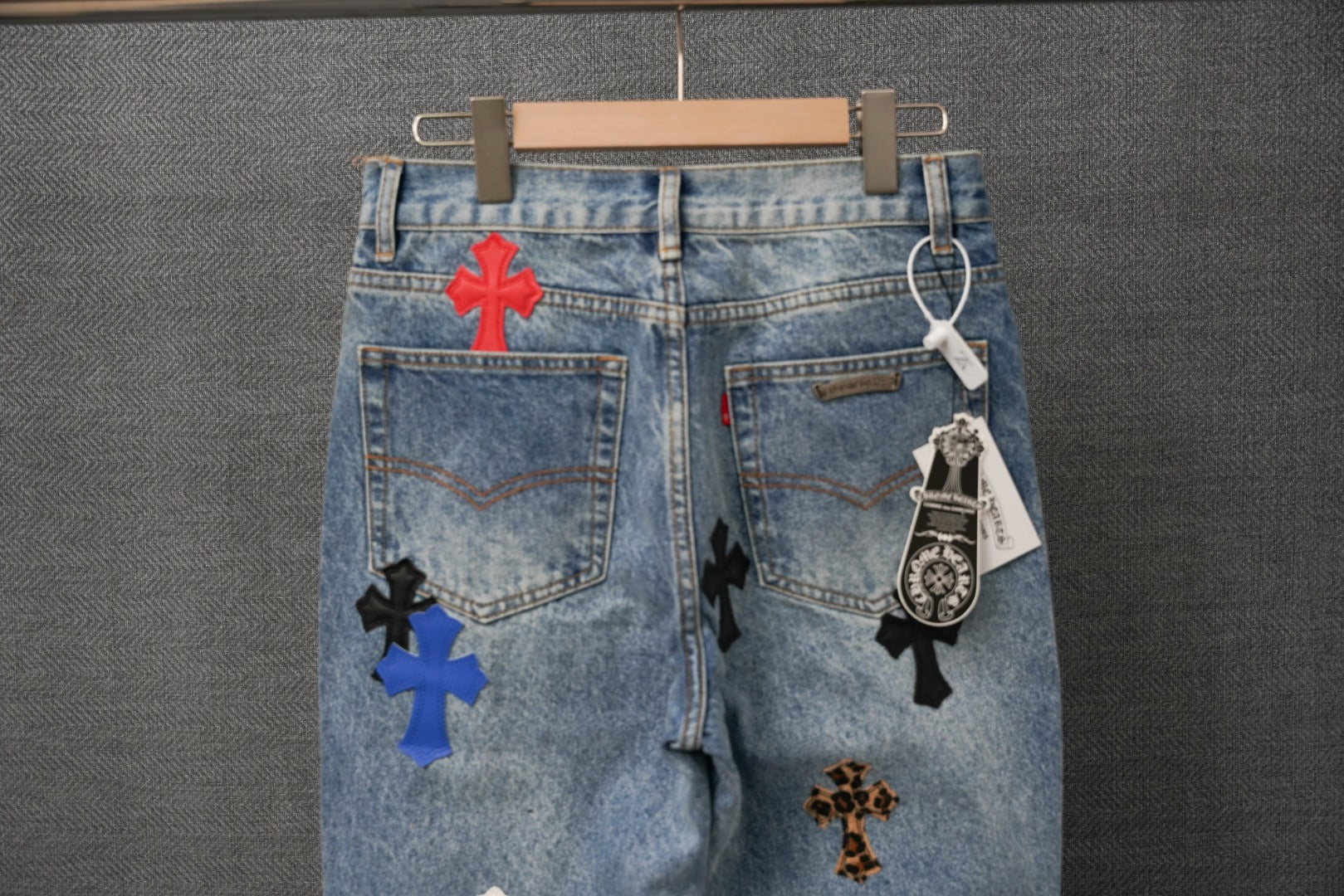 Denim jeans with multiple cross appliques and a hanging tag