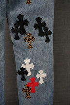 Denim jeans with mixed-color cross patches, including leopard and red