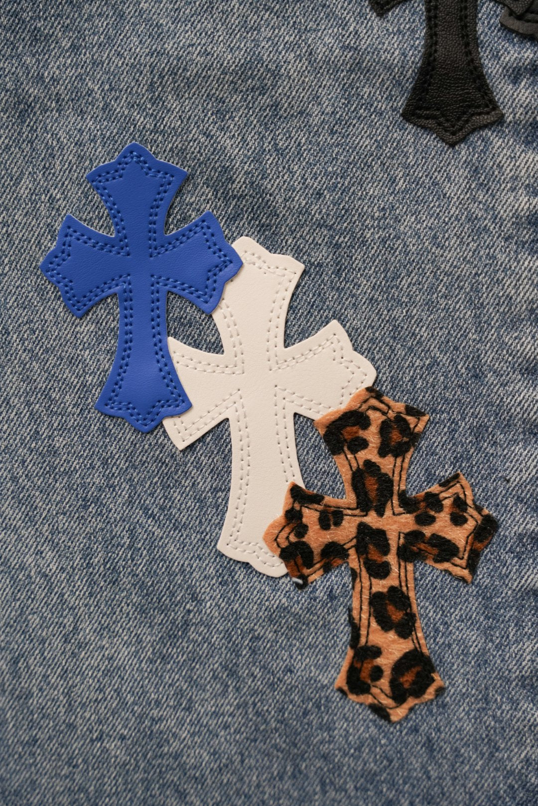 Blue denim pants with cross appliques in black, white, red, and leopard print