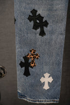 Blue denim pants with cross patches in black, white, and leopard print