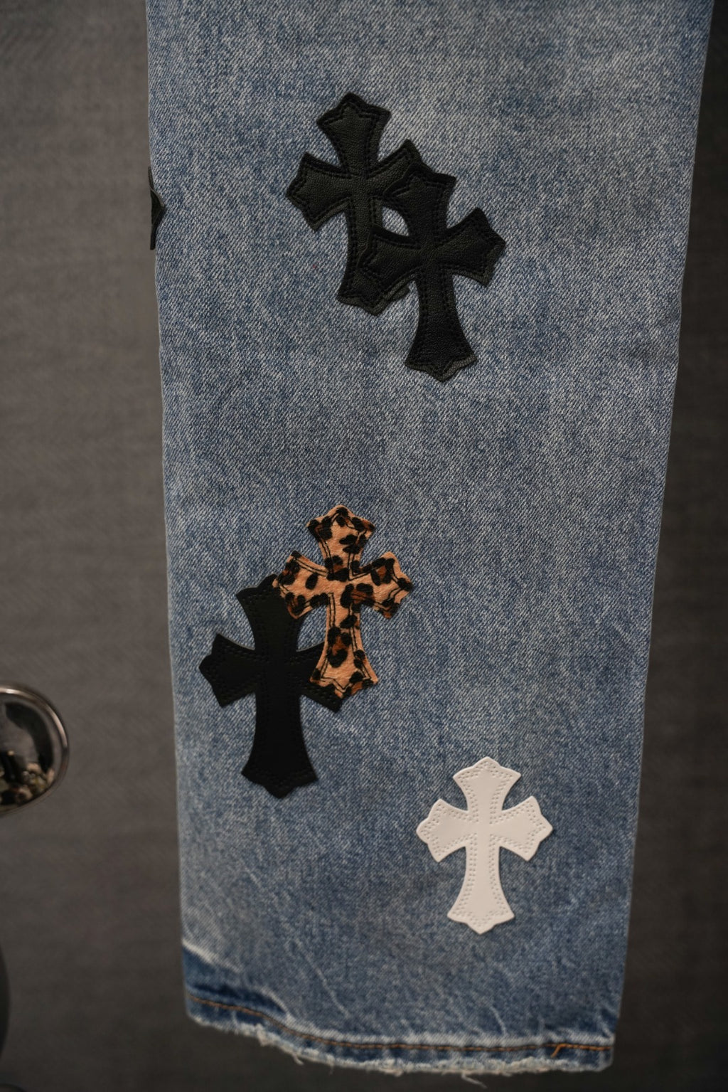 Denim jeans with black, leopard, and white cross patches