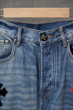 Light blue denim pants waistband and button fly with small decorative cross patch