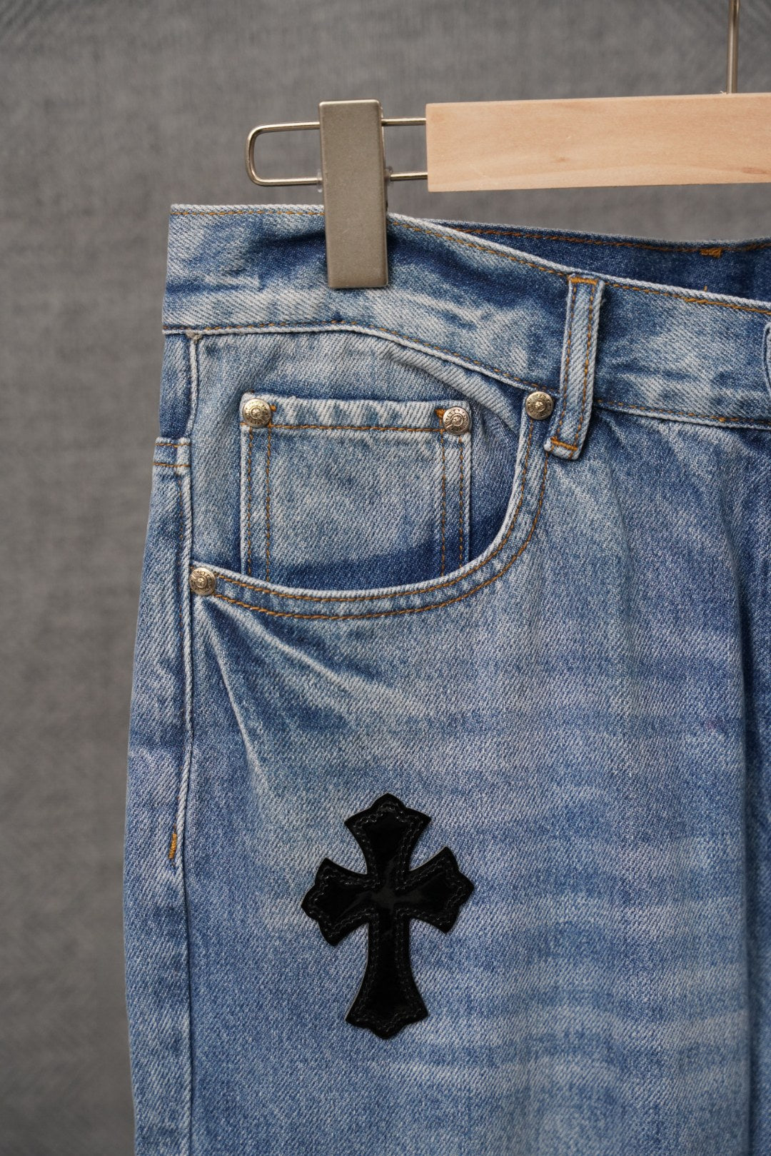 Light blue denim pants pocket and belt hardware with black cross patch