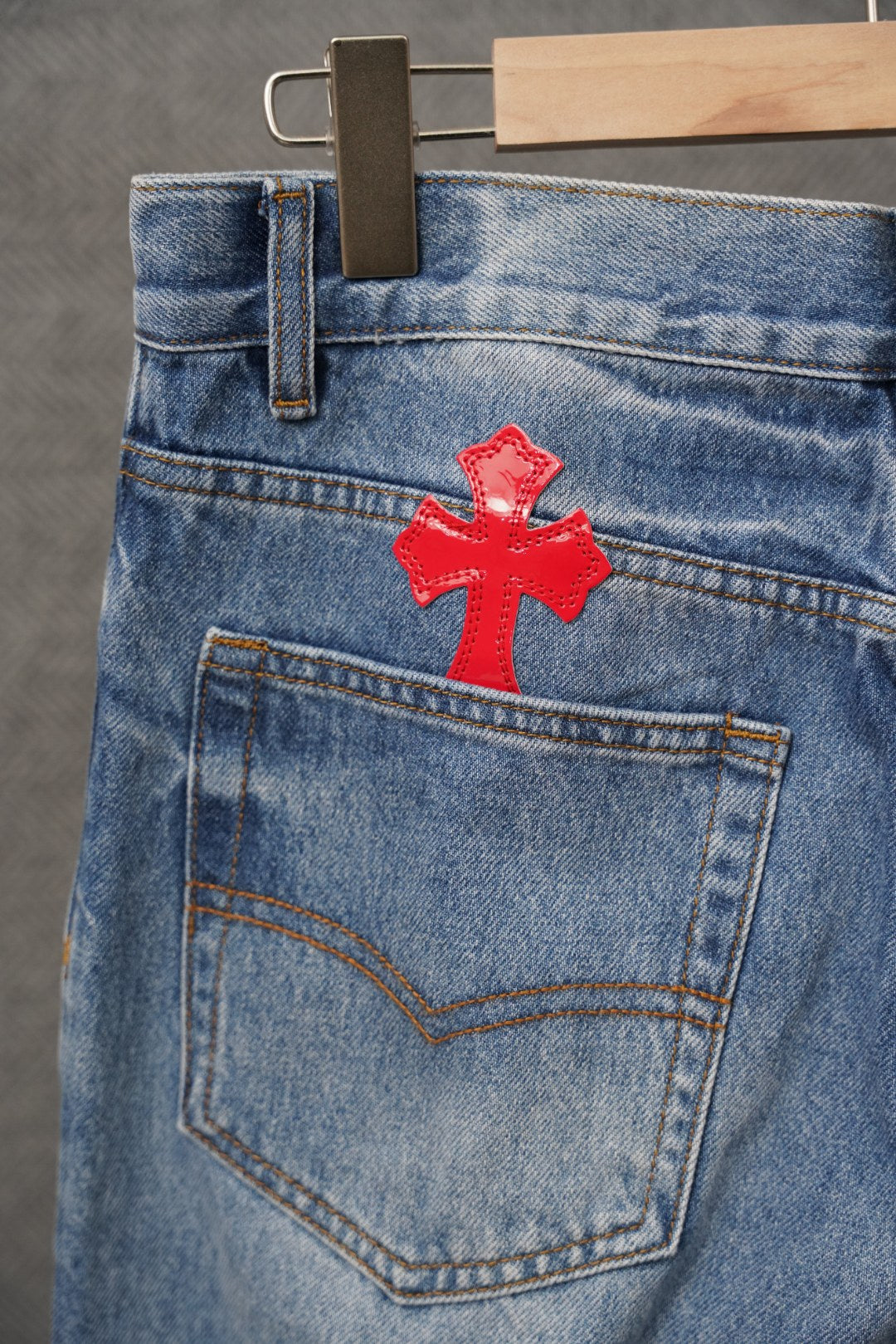 Light blue denim pants with red cross patch on back pocket.