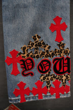 Denim Chrome pants with red cross patches, leopard graphic, and red lettering