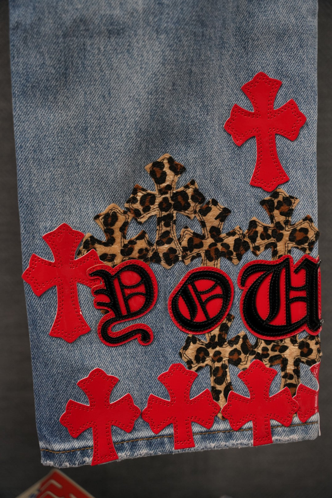 Chrome pants denim side with red crosses, leopard patches, and stylized red lettering