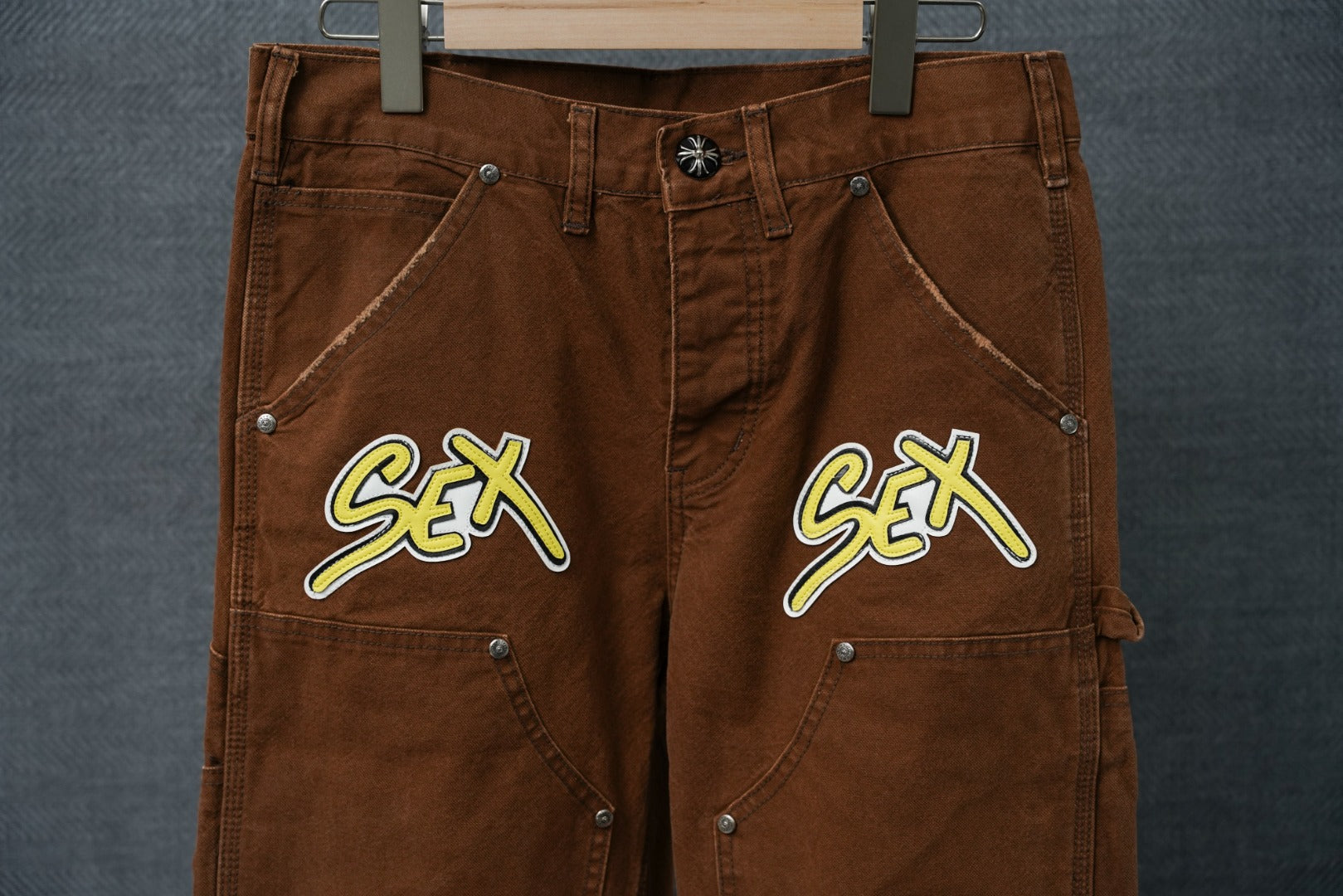 Brown cargo pants close-up of waistband and front patch pockets with “S€X”
