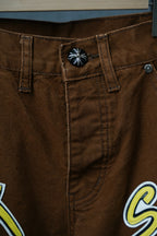 Brown cargo pants close-up of waistband, button, and stitched “S€X” logo patch