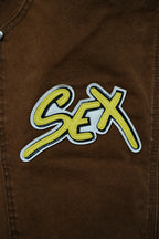 Brown cargo pants close-up of large “S€X” embroidered graphic patch