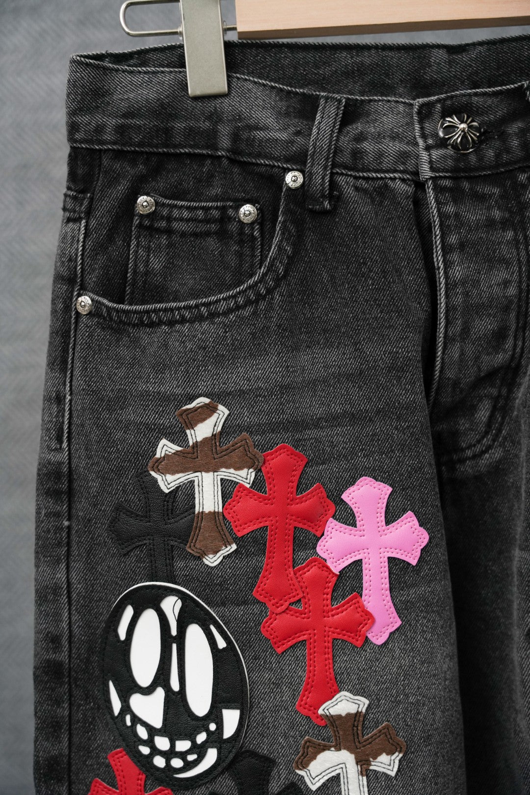 Black denim pants with double-button waistband and multicolor cross appliques