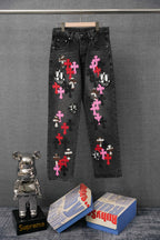 Dark denim pants with colorful cross patches and cartoon skull graphic on front