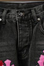 Black denim pants waistband with button and belt loops plus small graphic detail