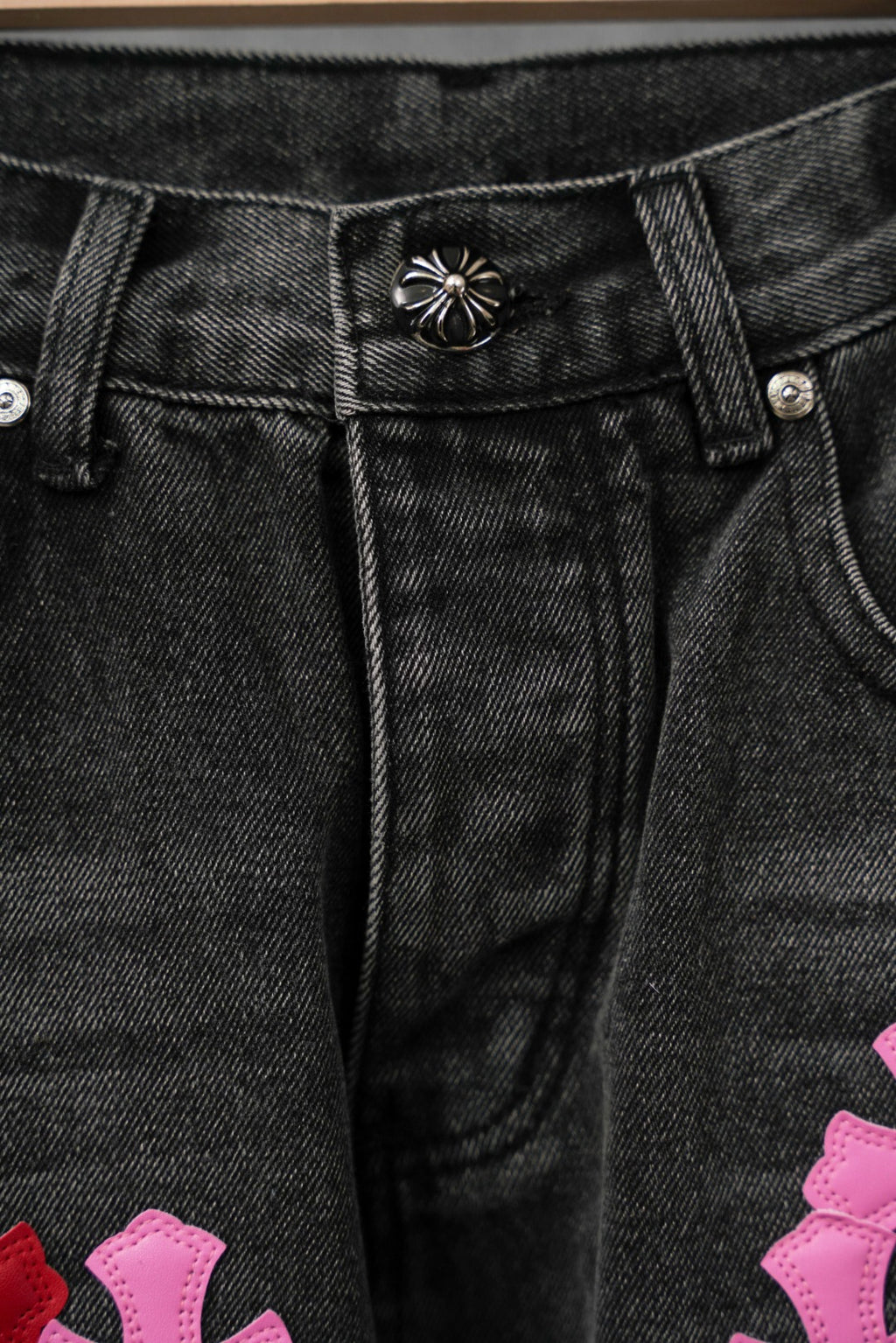 Dark denim pants waistband with metal button and stitched fly detail