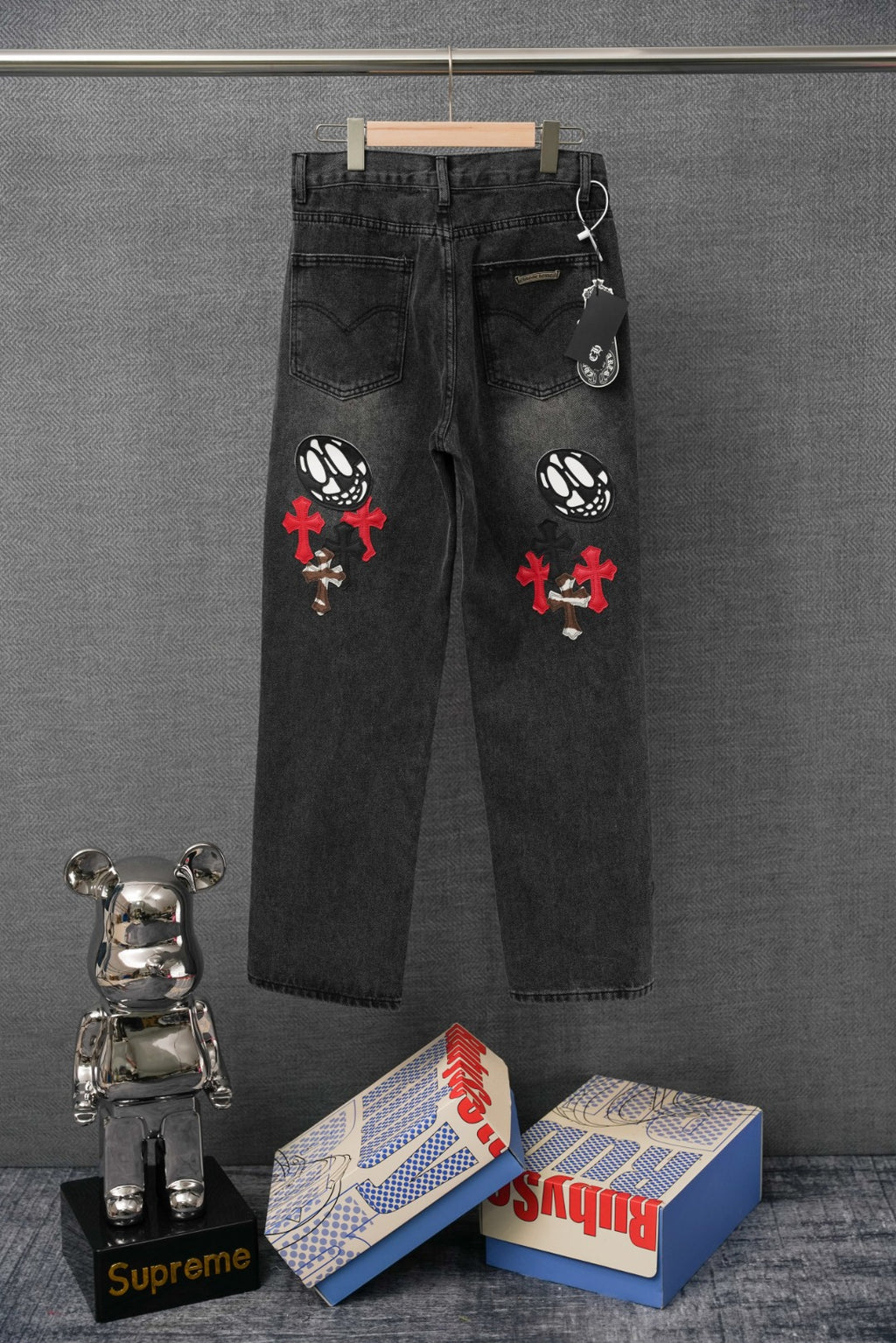 Dark denim pants with embroidered cross patches and skull graphic on back