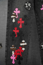 Dark denim pants with multicolor cross appliques and skull graphic detail