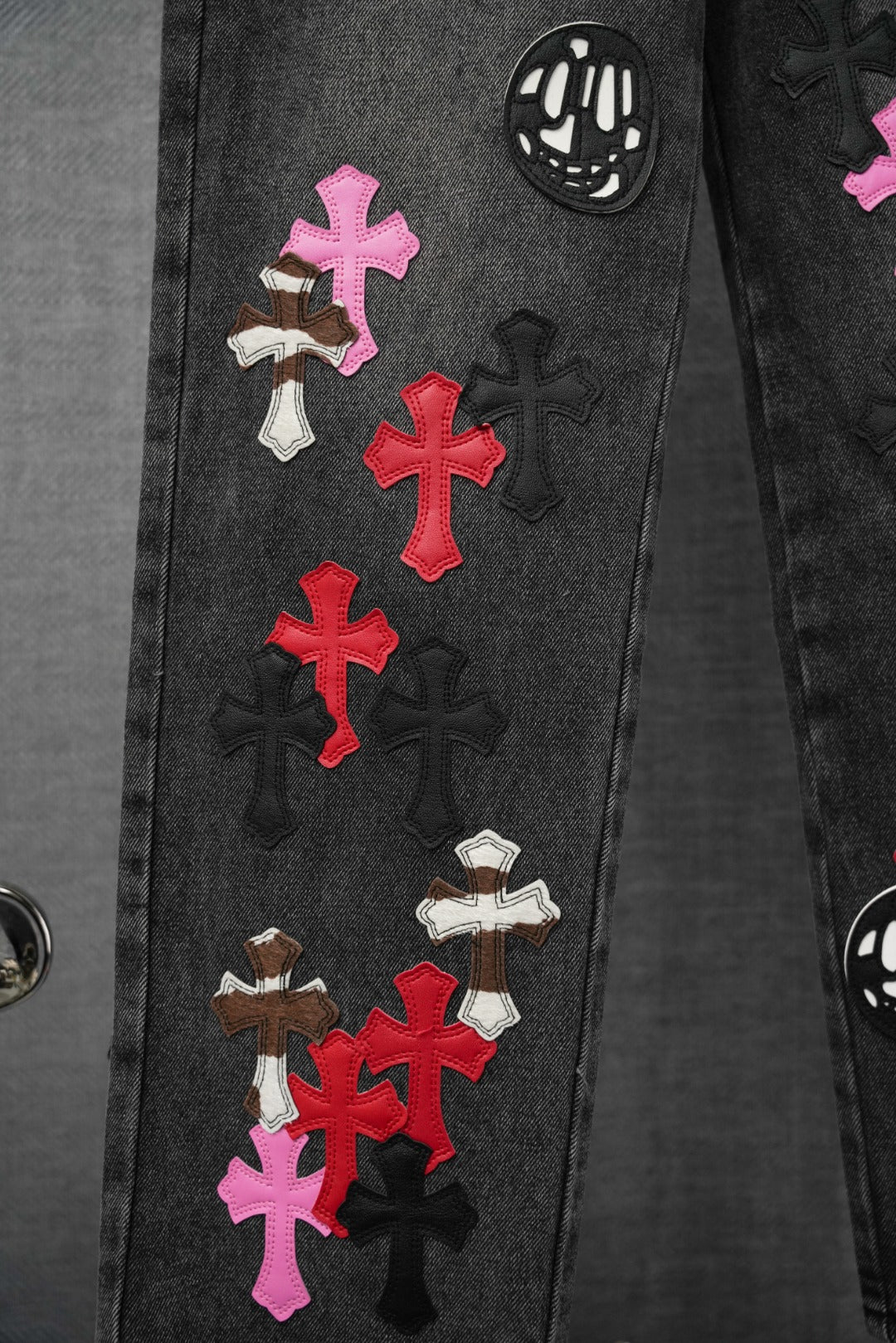 Dark denim pants with multicolor cross appliques and skull graphic detail
