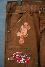 Brown cargo pants close-up of side pocket with cross applique and “Sex” logo