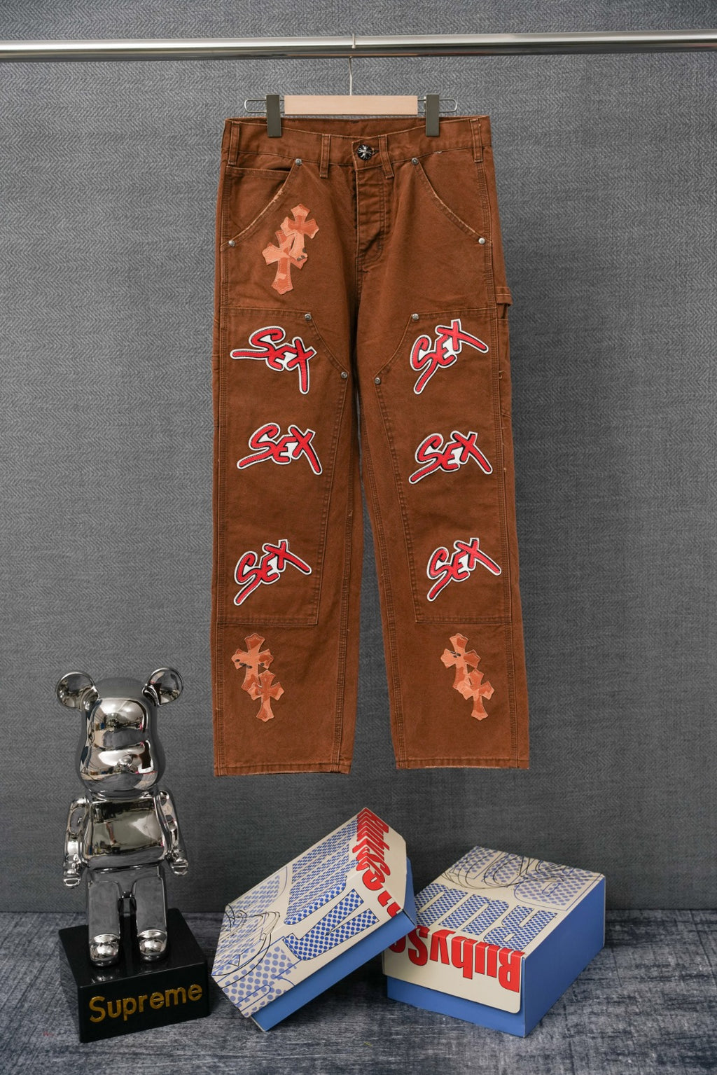 Brown cargo pants with cross appliques and colorful “SEX” patches on legs