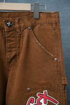 Brown cargo pants close-up with side pocket, belt loops, and “SEX” logo