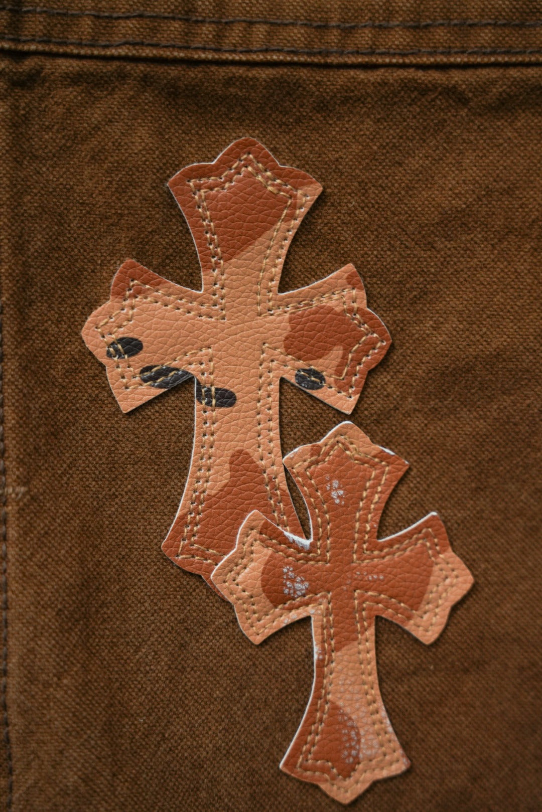 Brown cargo pants close-up of large cross applique patch with stitched details
