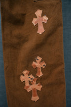 Brown chrome pants with three orange cross patches on thigh