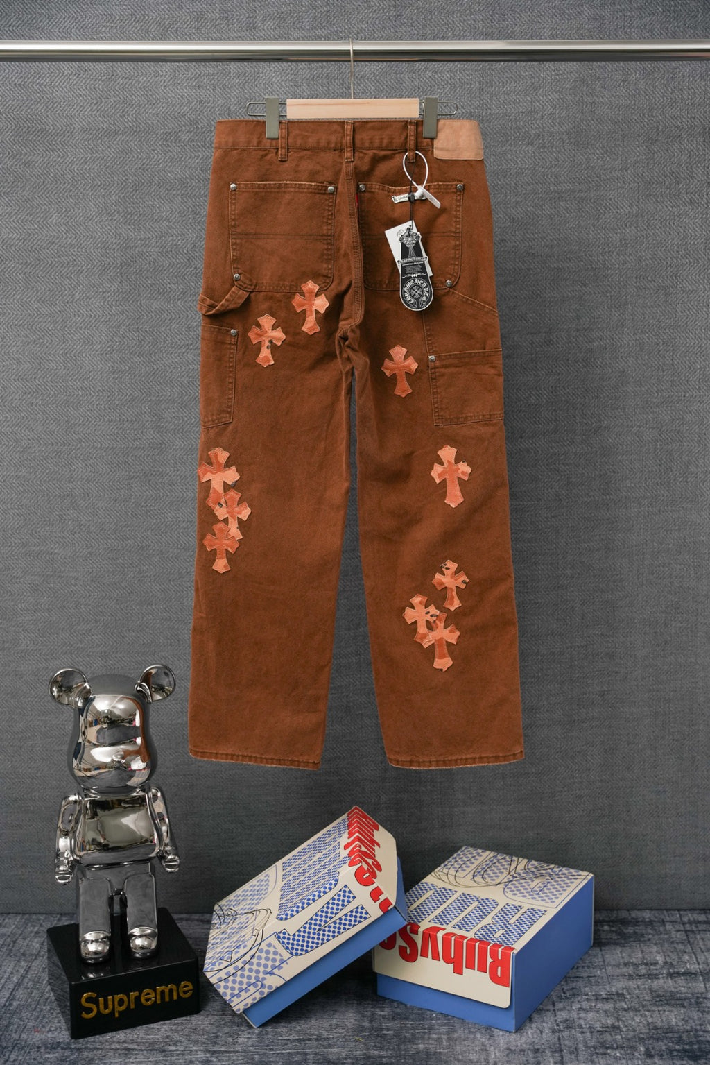 Brown cargo pants with cross appliques and “SEX” graphics; keychain tag at waistband
