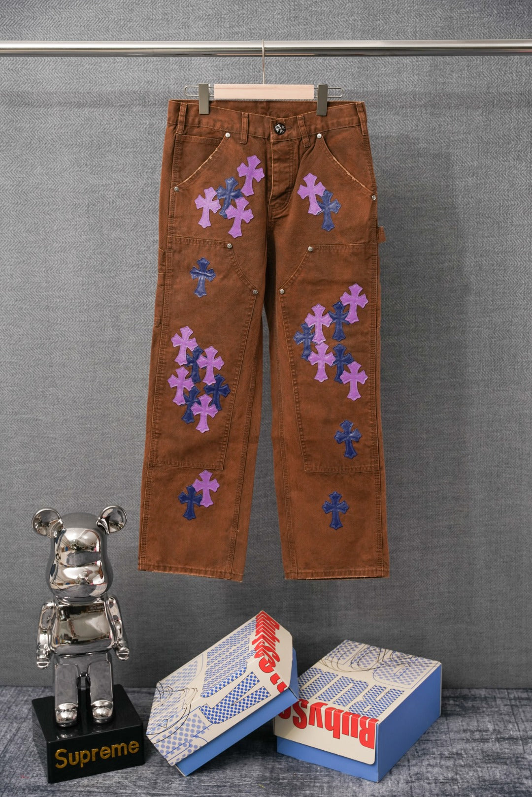 Brown jeans with purple and blue cross patches on front and back