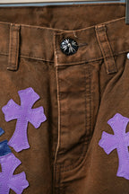 Close-up of brown jeans front with large purple cross patch detail