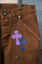 Close-up of brown jeans with purple and blue cross patches on thigh